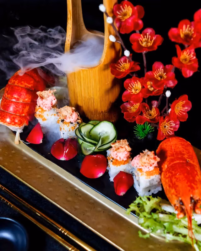 Composizione di sushi servita con scenografia di fumo e astice