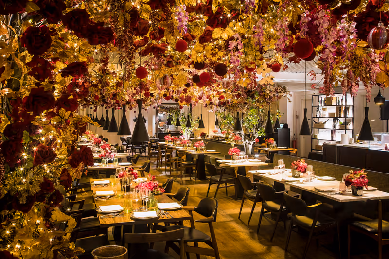 La sala del ristorante con tavoli apparecchiati sotto un soffitto di fiori
