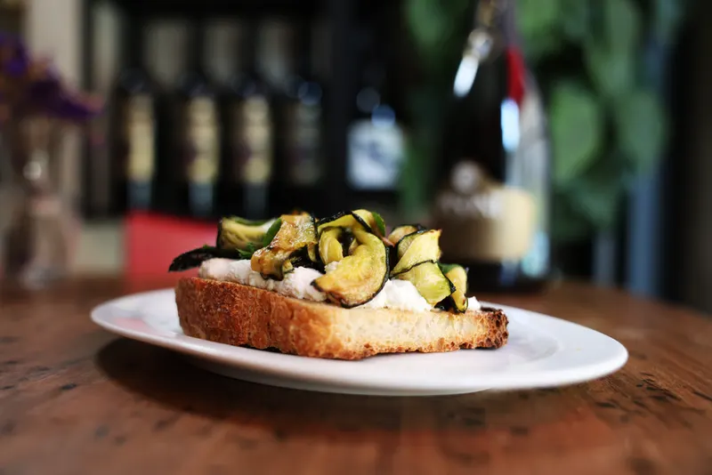 Crostone con zucchine davanti alle bottiglie