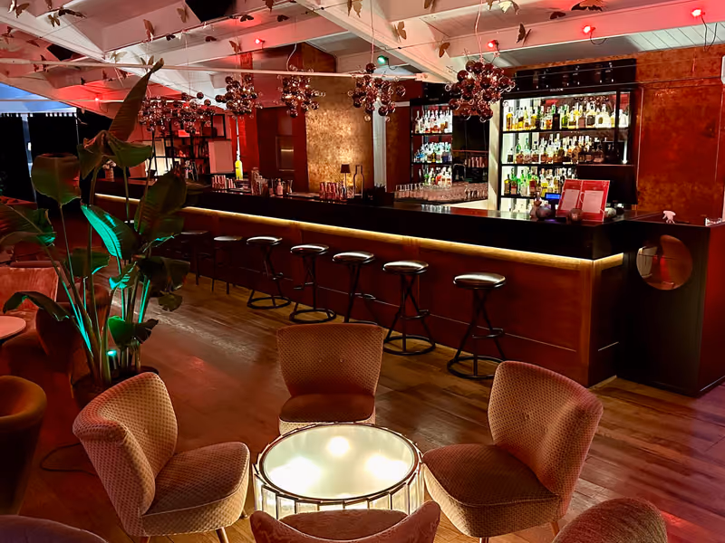 Il bancone del bar con sgabelli e bottiglie illuminate